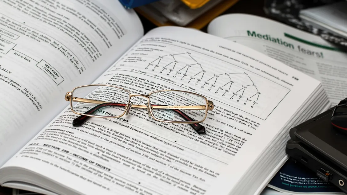 A folded pair of glasses on an open book.